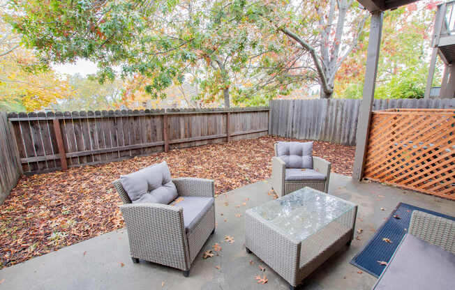 a patio with chairs and a table in front of a fence