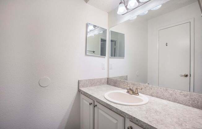 A bathroom with a sink, mirror, and light fixture.