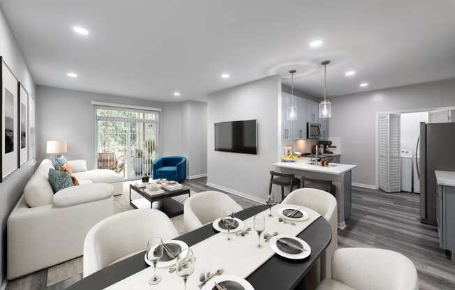 a living room and kitchen with white furniture and a tv