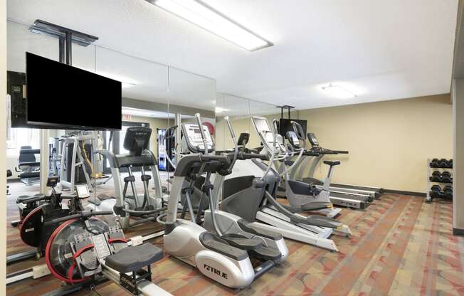 a room filled with cardio equipment and a flat screen tv