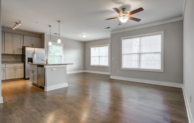 living and dining areas with hardwood-style flooring, ceiling fan, and kitchen in the background