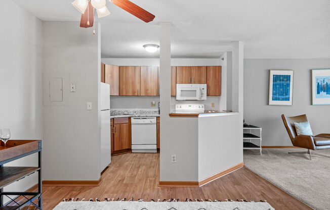 an open kitchen and living room with white appliances and wood flooring