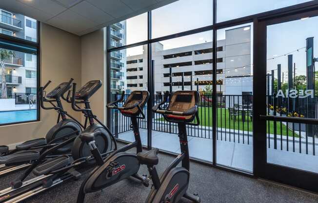 cardio bikes in the gym of a building with a view of theenced in patio