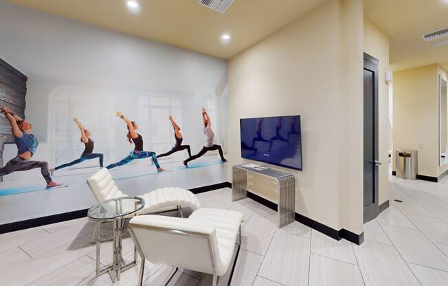 a yoga studio with white chairs and a tv on the wall