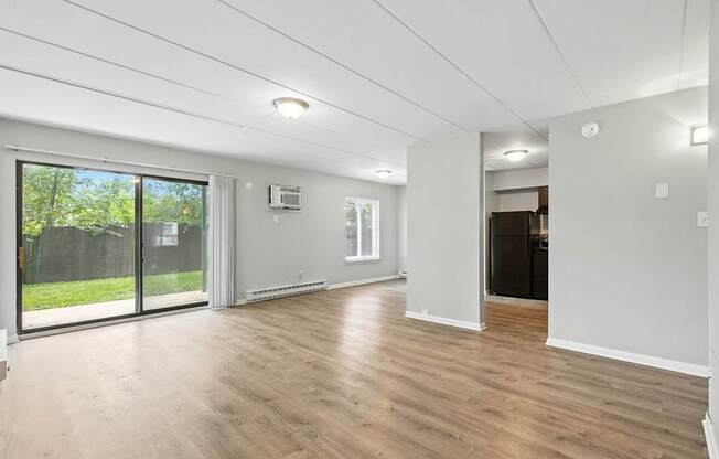 A spacious room with wooden flooring and white walls.