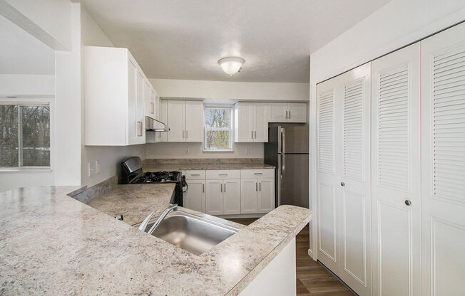 an end style kitchen with white cabinets and a window at Canal 2 Apartments, Lansing, Michigan
