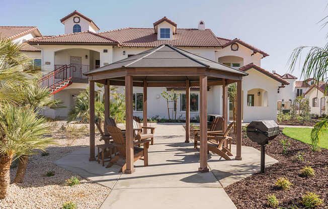 A gazebo is in the middle of a patio with chairs around it.