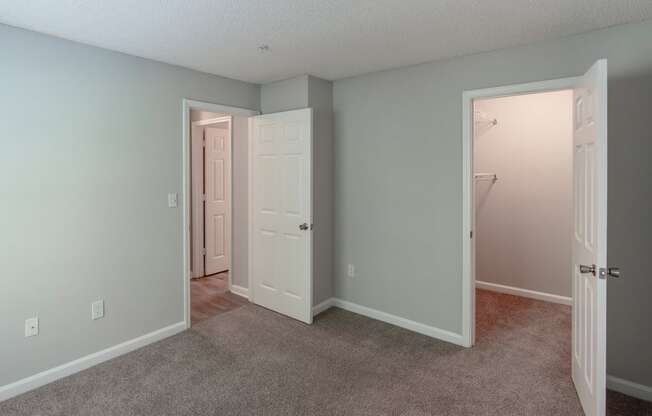 an empty bedroom with a closet and a door to a bathroom