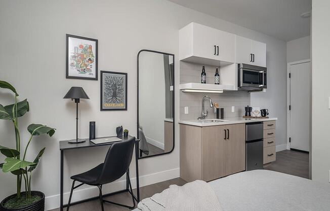 a bedroom with a bed and a desk with a mirror in front of it and a kitchen