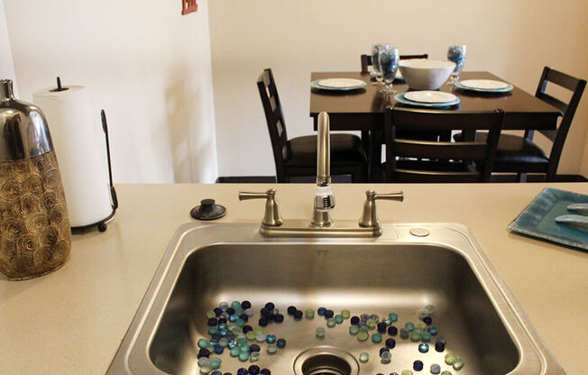 a sink with marbles in it and a dining room table and chairs in the background