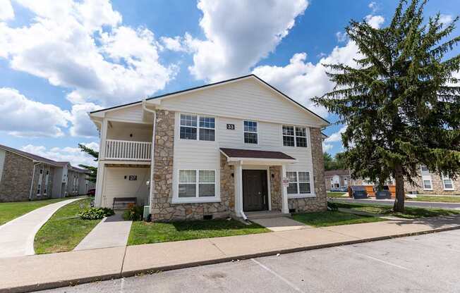 a white and stone house with a sidewalk in front of it