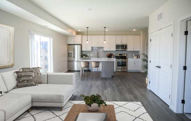 a living room and kitchen with white cabinets and a white couch