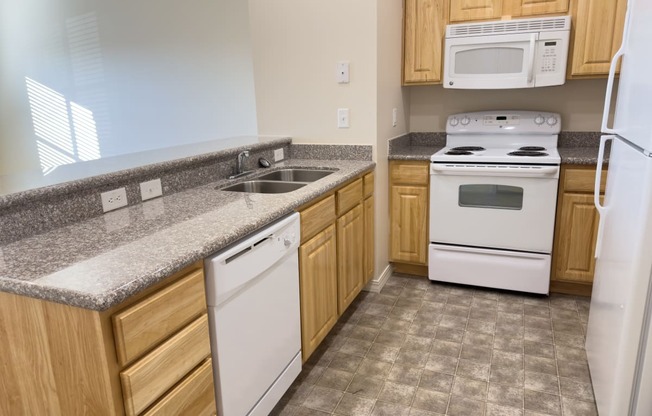 Liberty Bend Townhome Apartments, Sandy, Utah kitchen with white appliances and granite counter tops and wooden cabinets