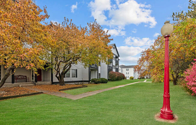 A red street lamp stands on a green lawn.