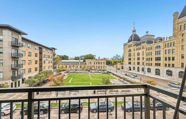 A view from a balcony overlooking a parking lot and buildings.