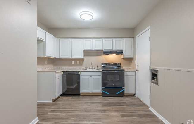 an empty kitchen with white cabinets and a black stove and oven