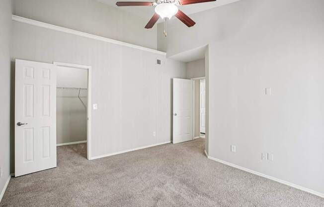 A room with a ceiling fan and carpeted floor.
