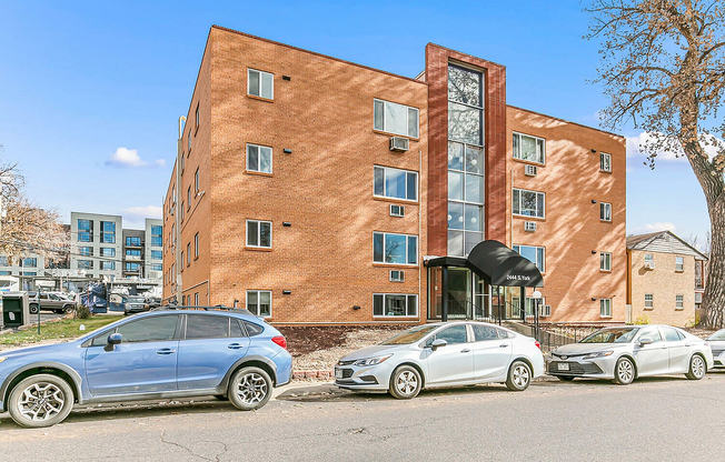 Charming red brick apartment building with modern design, featuring large windows and a welcoming entrance, set in a vibrant neighborhood.