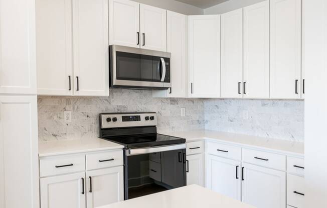 a kitchen with white cabinets and a black stove and microwave