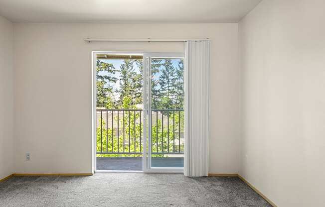 a bedroom with a sliding glass door and a balconyat Mill Pond Apartments, Auburn, WA
