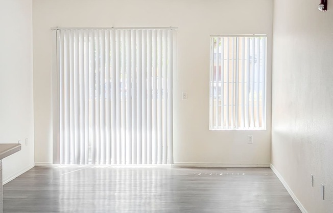 A room with a ceiling fan and two windows with blinds.