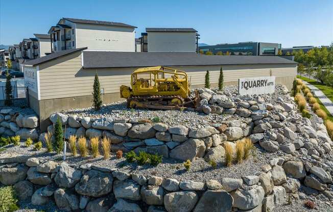 a large rock retaining wall in front of a house with a yellow bulldozer parked