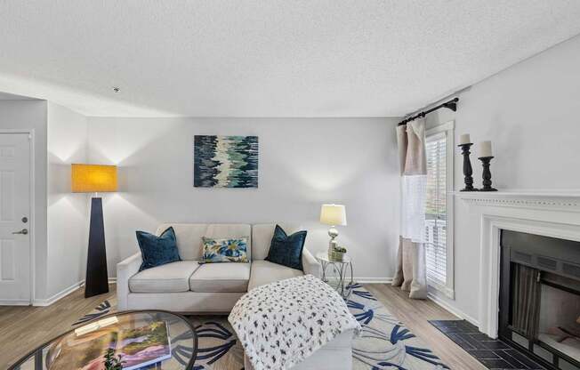 A living room with a white couch and a painting on the wall.