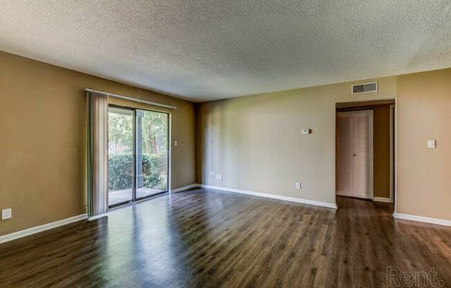 an empty living room with wood floors and a sliding glass door