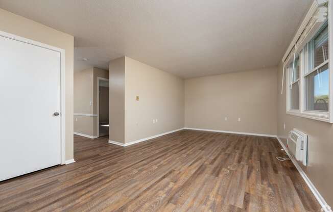 an empty living room with wood flooring and a window