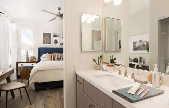 a bedroom and a bathroom with a sink and a mirror