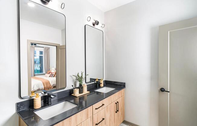 Dual vanity with sleek black counters, wood cabinetry, and matte black fixtures just steps from the bedroom.