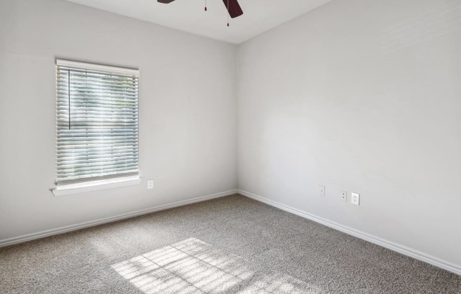 an empty room with a window and a ceiling fan