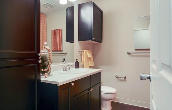 A bathroom with a toilet, sink, and cabinets.
