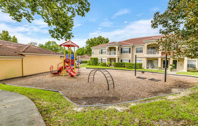 A playground with a swing set and a sandbox in front of a building.