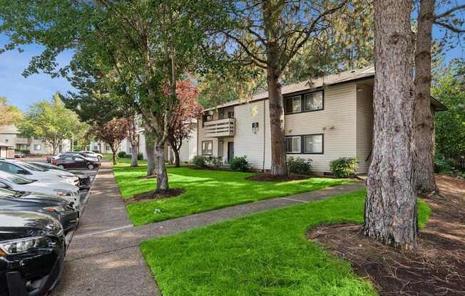 A row of cars parked on a sidewalk in front of apartment buildings.