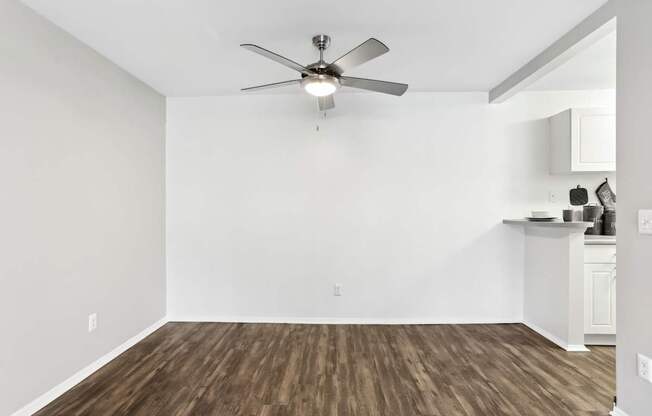 A room with a ceiling fan and wooden flooring.
