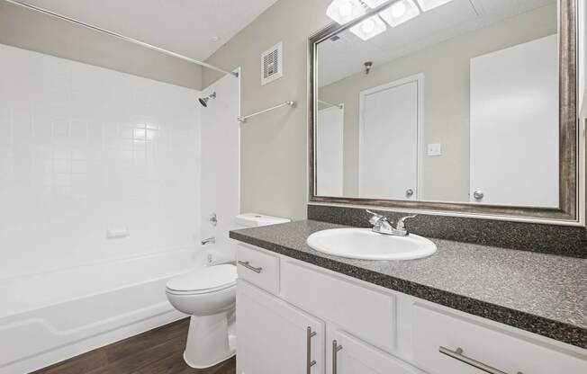 B1 bathroom with a toilet, sink, and mirror at Jefferson Place Apartments in Irving, TX