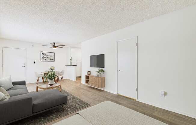 A living room with a grey couch and a white ceiling fan.