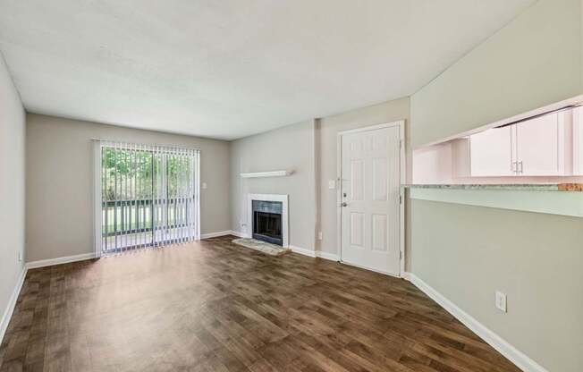 A living room with a fireplace and a glass door leading to a balcony at Gwinnett Square Apartments in Duluth, GA