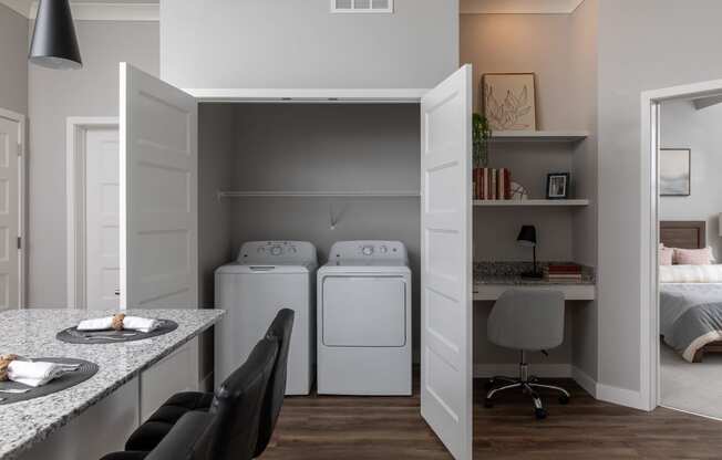 a laundry room with washer and dryer and a desk in a room at The Edison at Maple Grove, Maple Grove