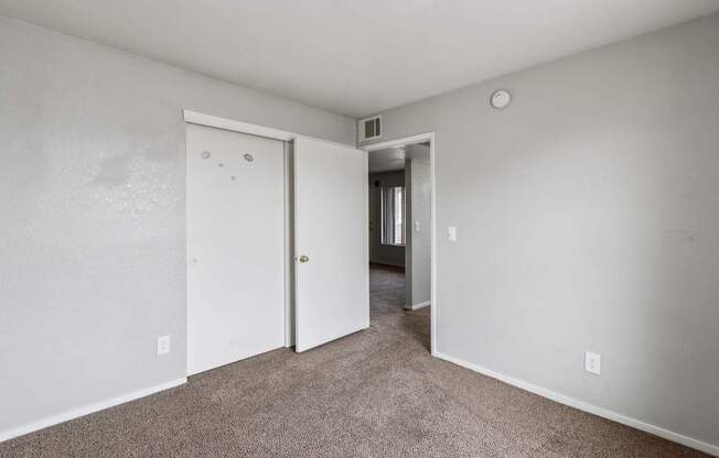 A room with a carpeted floor and two doors.