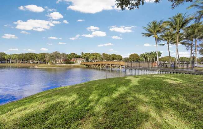 A serene park with a lake, trees, and a clear sky.