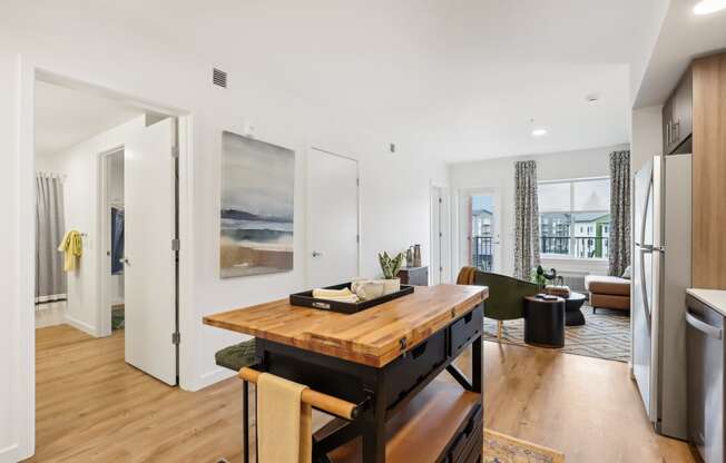 a living room with a wooden table and a kitchen