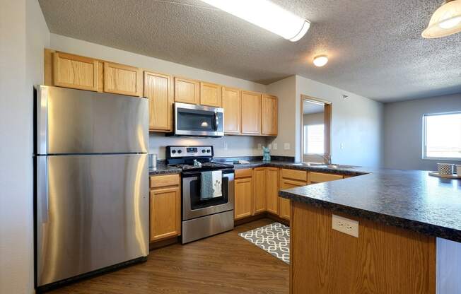 a kitchen with stainless steel appliances and wooden cabinets. Fargo, ND East Bridge Apartments