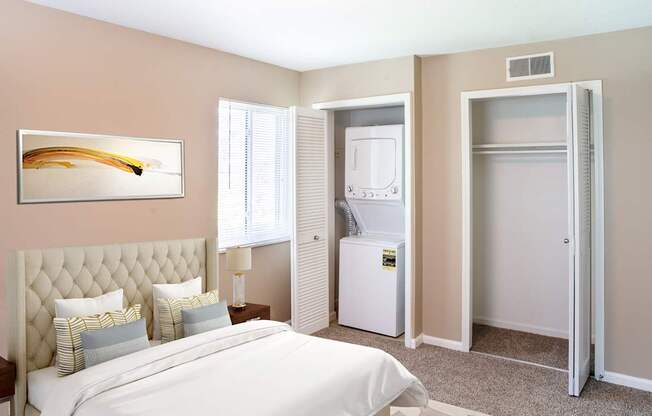 A bedroom with a bed, a painting, and a window.