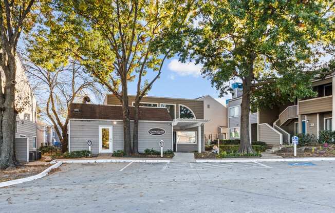 an empty parking lot in front of a building with trees