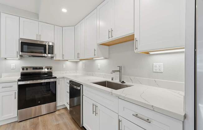 A modern kitchen with white cabinets and stainless steel appliances.