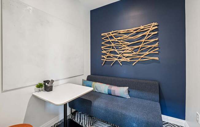 A blue couch with a white table and a wall art.