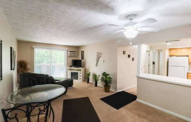 an open living room with a kitchen and a ceiling fan