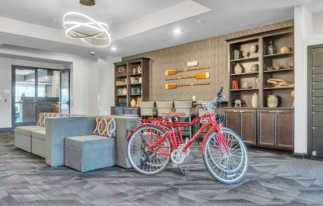 A red bicycle is parked in a room with a grey carpet.
